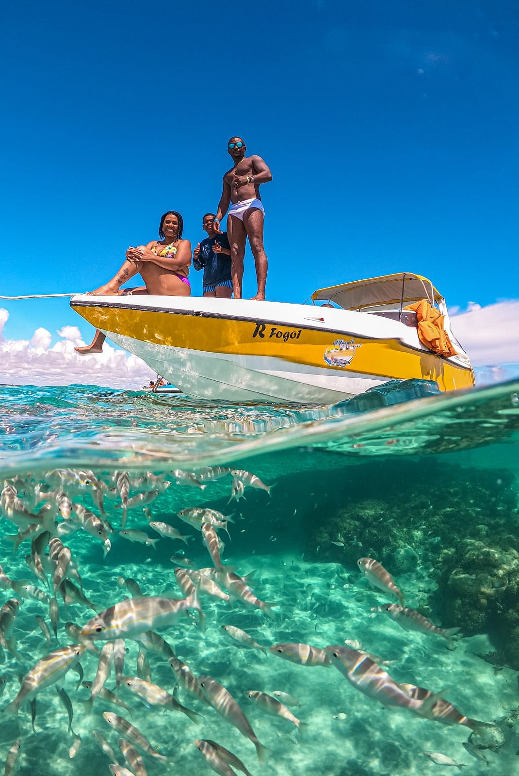 Lancha em águas cristalinas com cardume de peixes